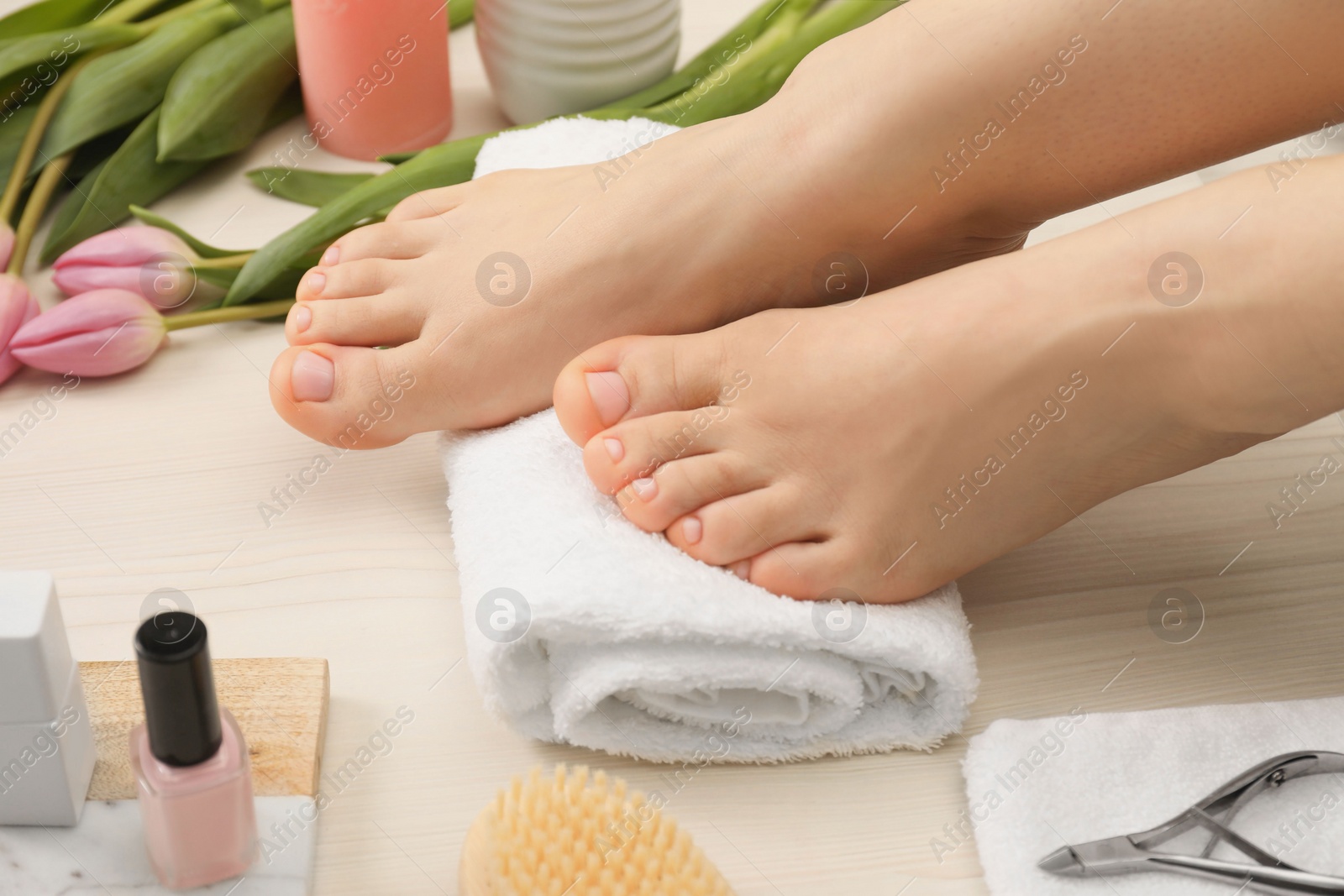 Photo of Woman with neat toenails after pedicure procedure on white wooden floor, closeup