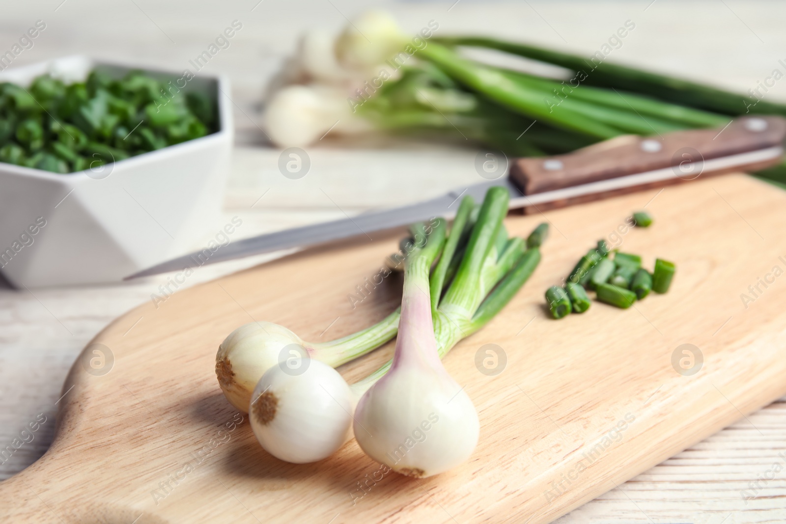 Photo of Wooden board with fresh green onion, closeup