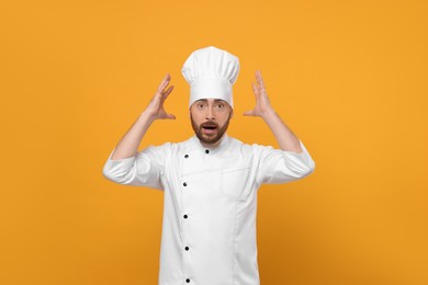 Emotional mature male chef on orange background