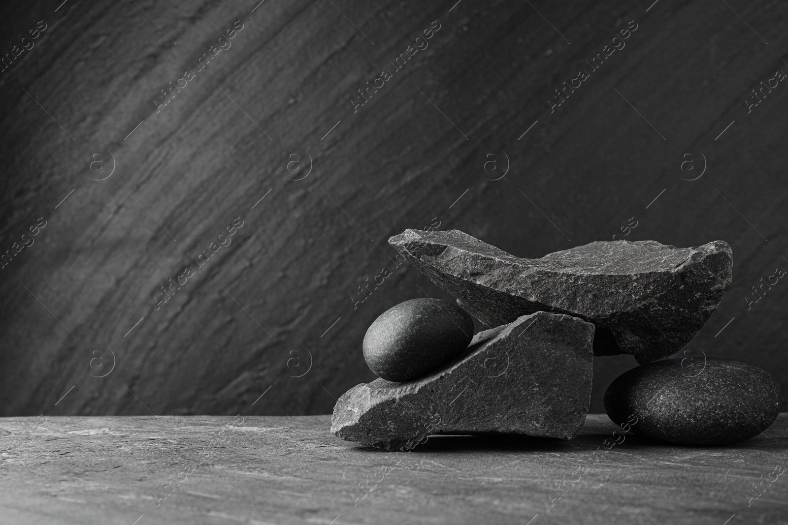 Photo of Presentation for product. Podium made of different stones on grey textured background. Space for text