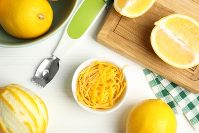 Lemon zest and fresh fruits on white wooden table, flat lay