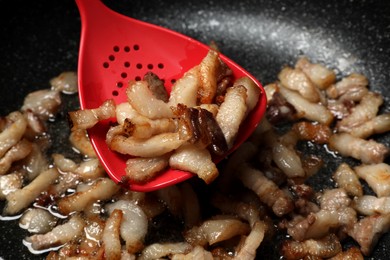 Frying cracklings in cookware, closeup. Pork lard