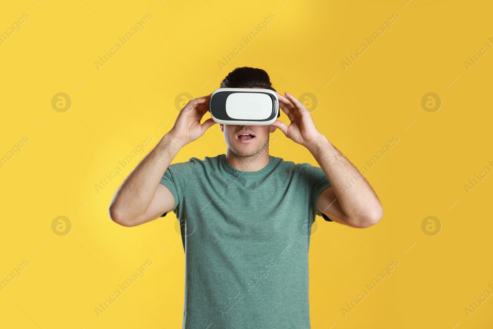 Photo of Man using virtual reality headset on yellow background