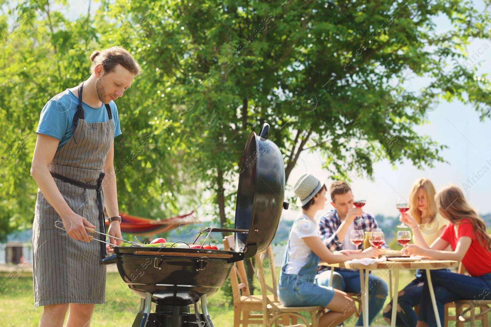 Photo of Young people having barbecue with modern grill outdoors