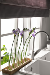 Photo of Beautiful freesia flowers near window in kitchen