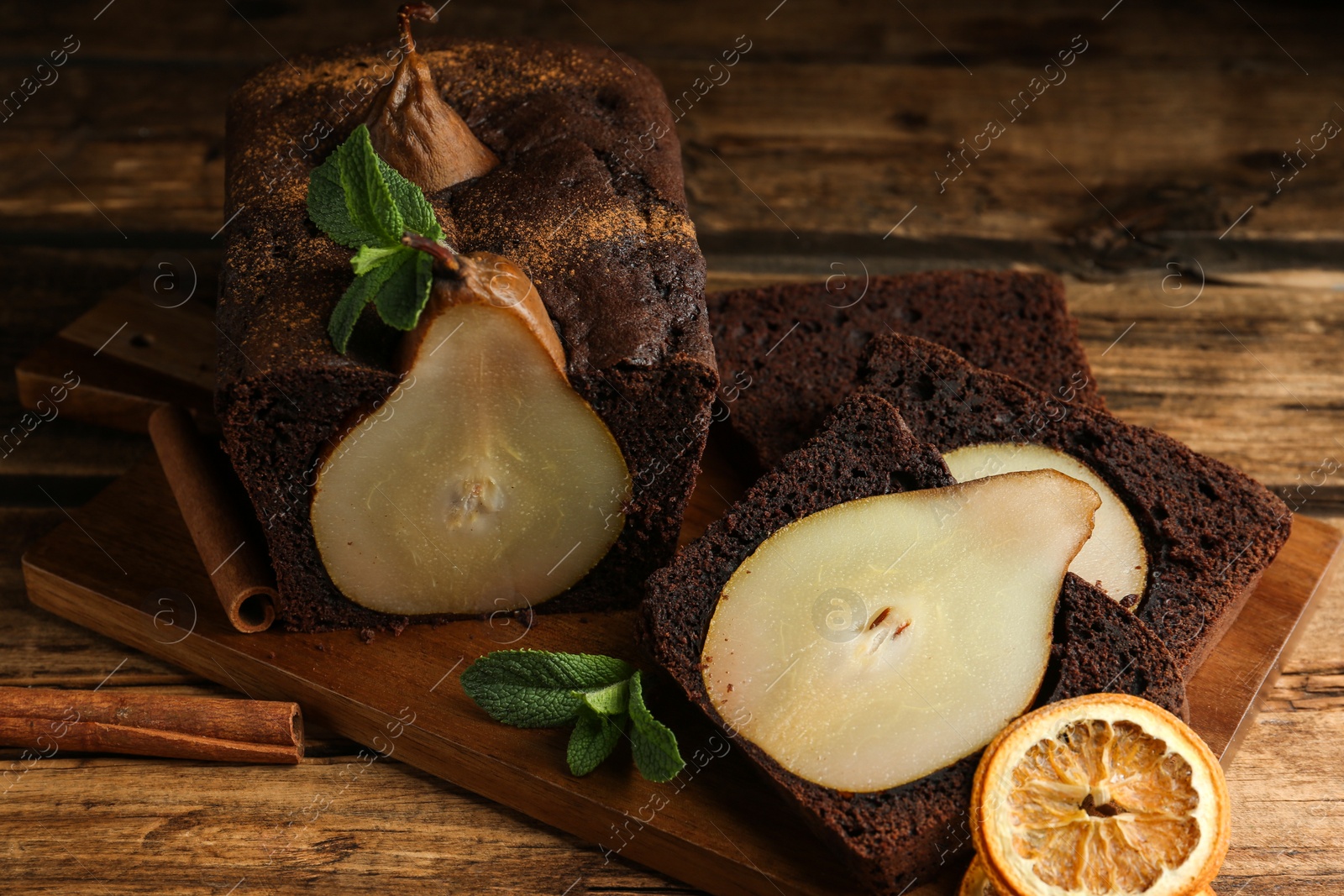 Photo of Tasty pear bread with mint, cinnamon and dried orange slices on wooden table. Homemade cake