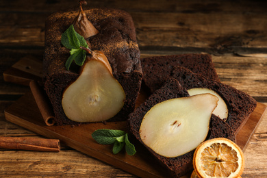 Photo of Tasty pear bread with mint, cinnamon and dried orange slices on wooden table. Homemade cake