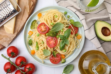 Photo of Plate of delicious pasta primavera and ingredients on white table, flat lay
