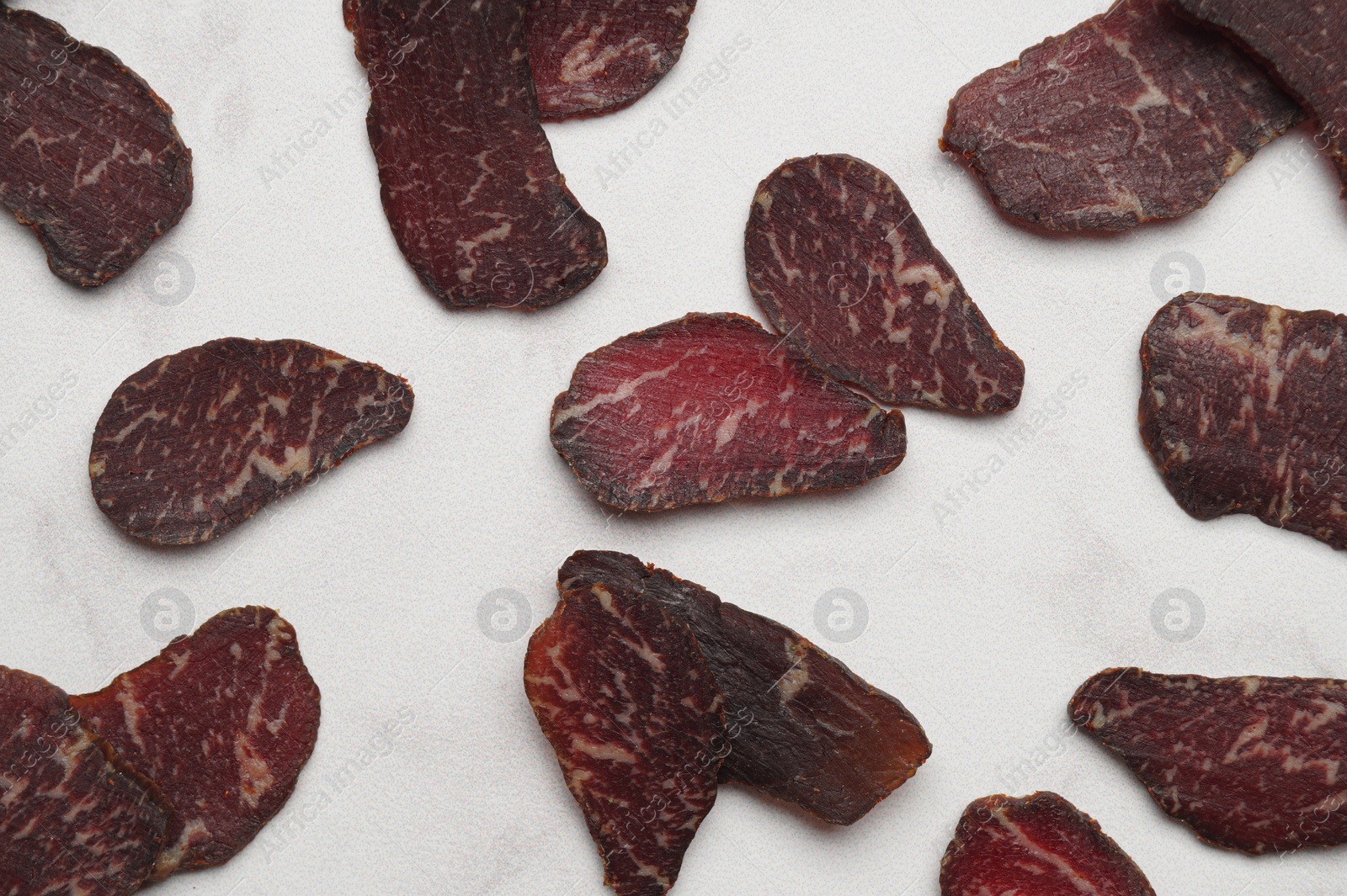 Photo of Delicious beef jerky on white table, flat lay