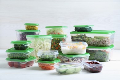 Photo of Set of plastic containers with fresh food on white wooden table