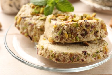 Photo of Tasty halva with pistachios and mint on table, closeup
