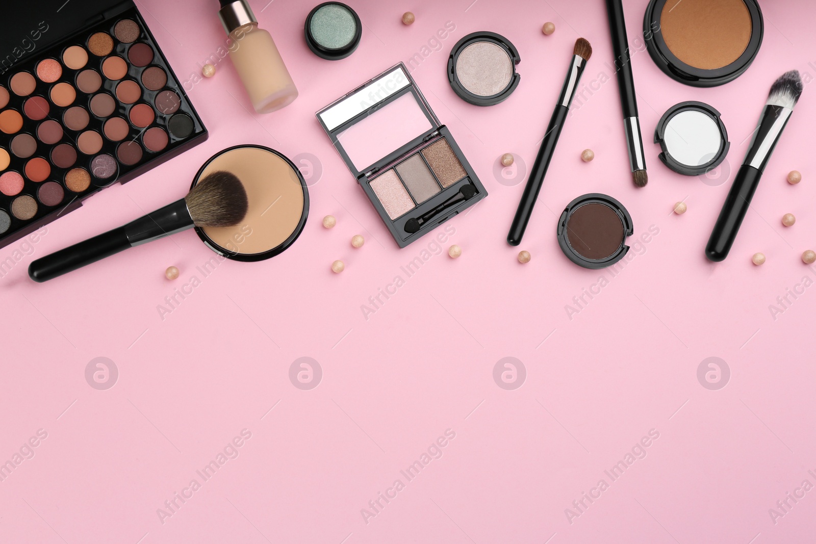 Photo of Different makeup brushes and cosmetic products on pink background, flat lay. Space for text