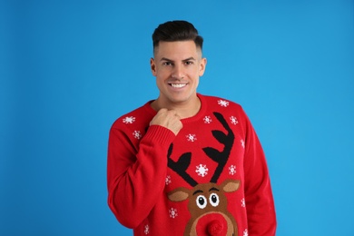 Handsome man in Christmas sweater on blue background