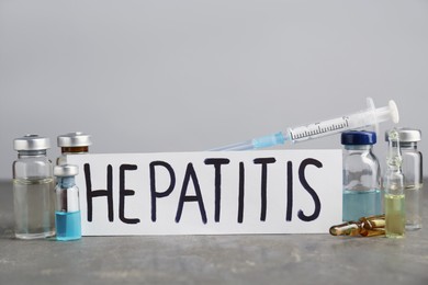 Photo of Word Hepatitis and medical supplies on grey table