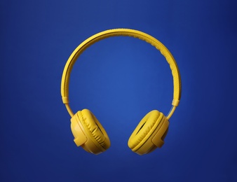 Stylish modern headphones with earmuffs on color background