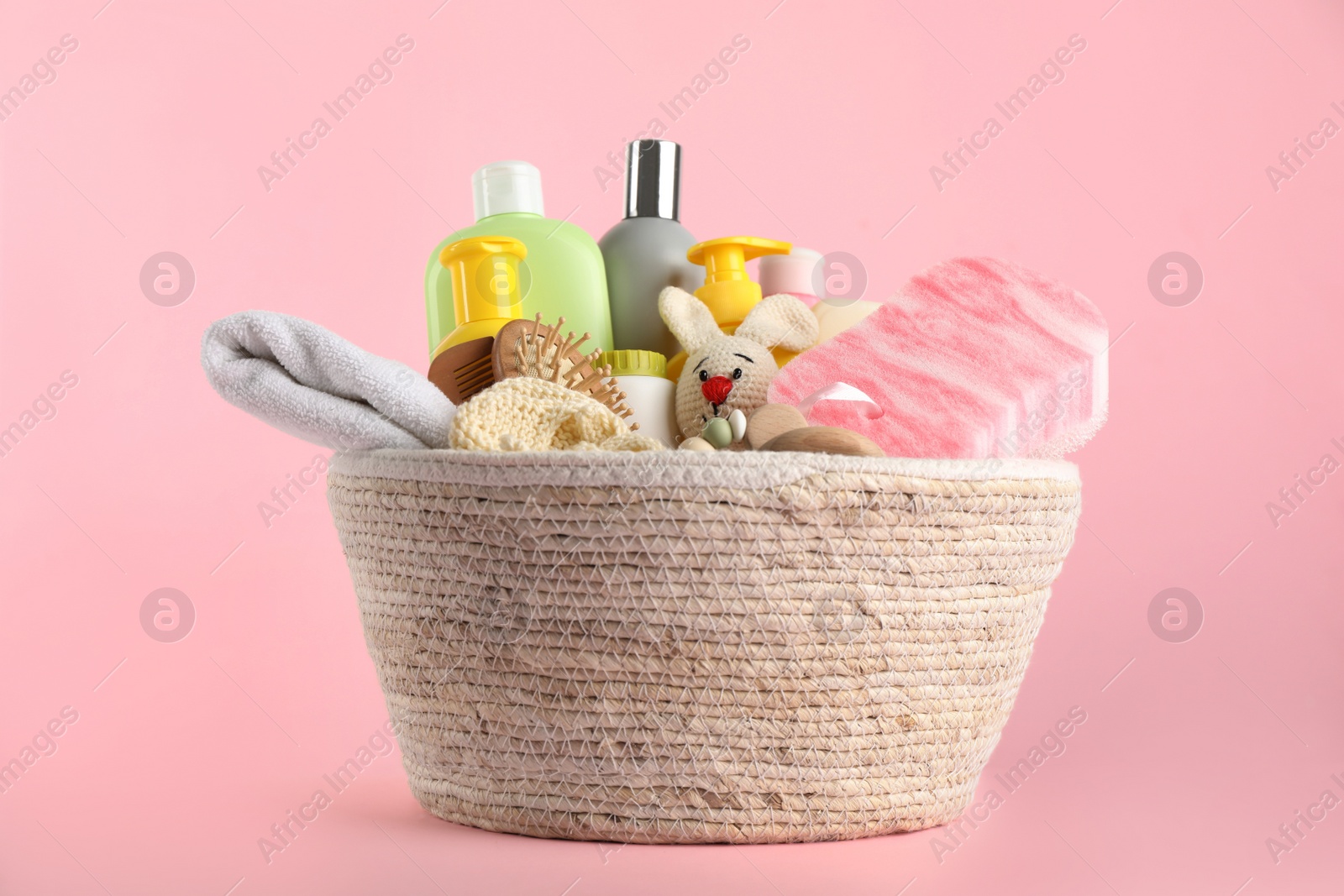 Photo of Basket with baby cosmetics and accessories on pink background