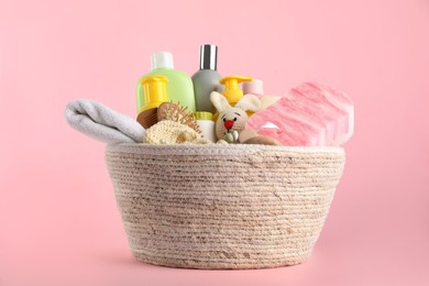 Basket with baby cosmetics and accessories on pink background