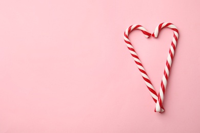Photo of Flat lay composition with candy canes on pink background. Space for text