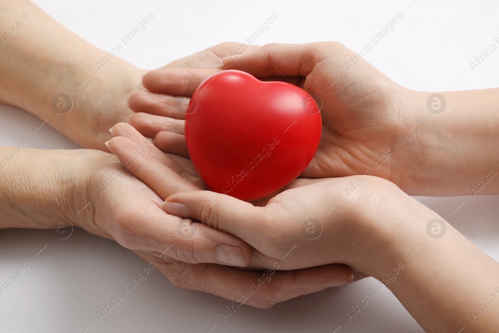 Photo of Young and elderly women holding red heart on white background, closeup