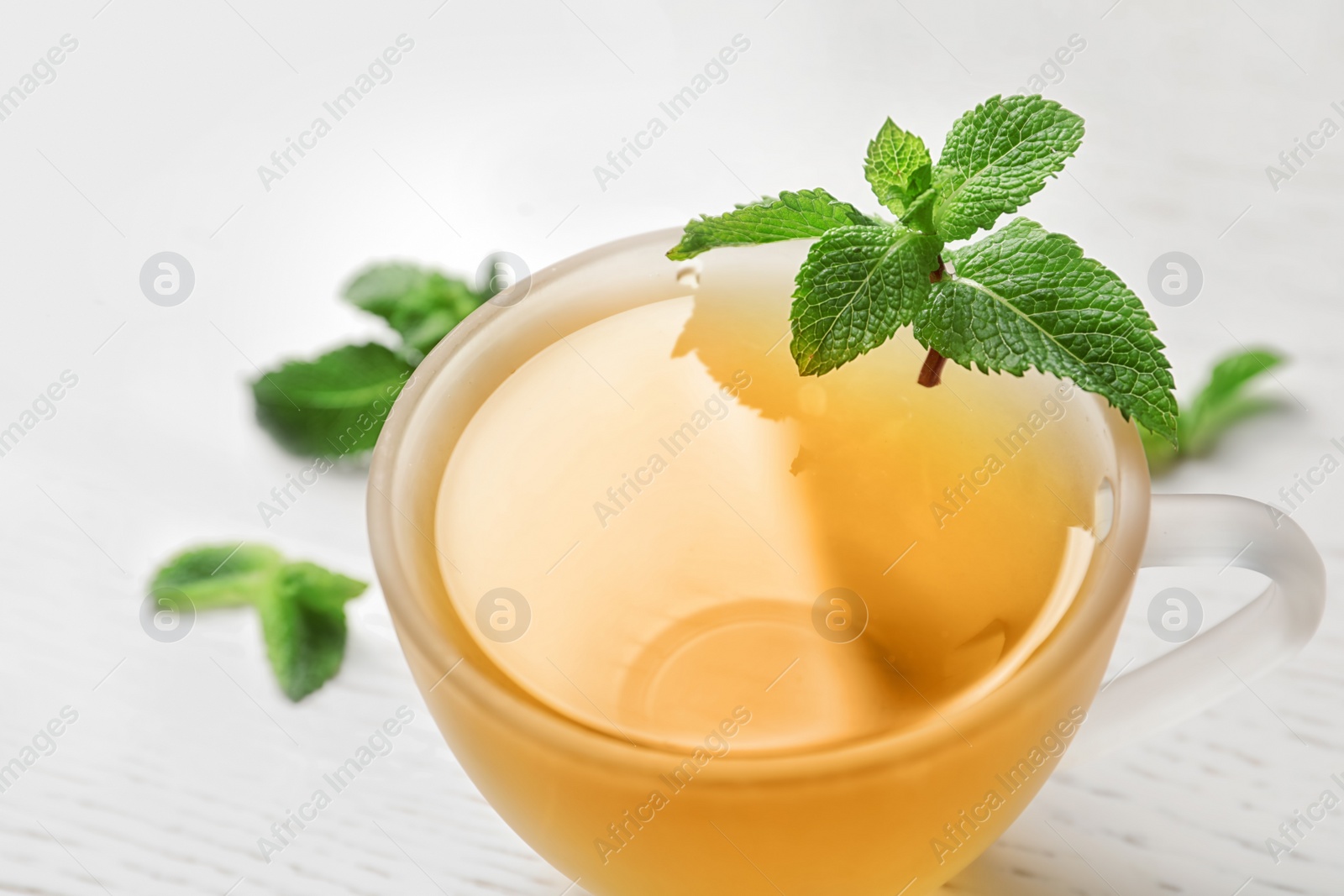 Photo of Cup with hot aromatic mint tea and fresh leaves, closeup