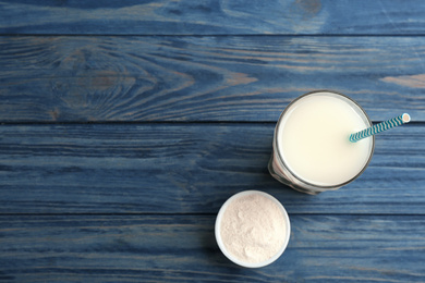 Photo of Protein shake and powder on blue wooden table, flat lay. Space for text