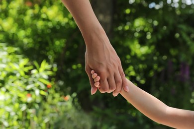 Mom and her child holding hands in park, closeup