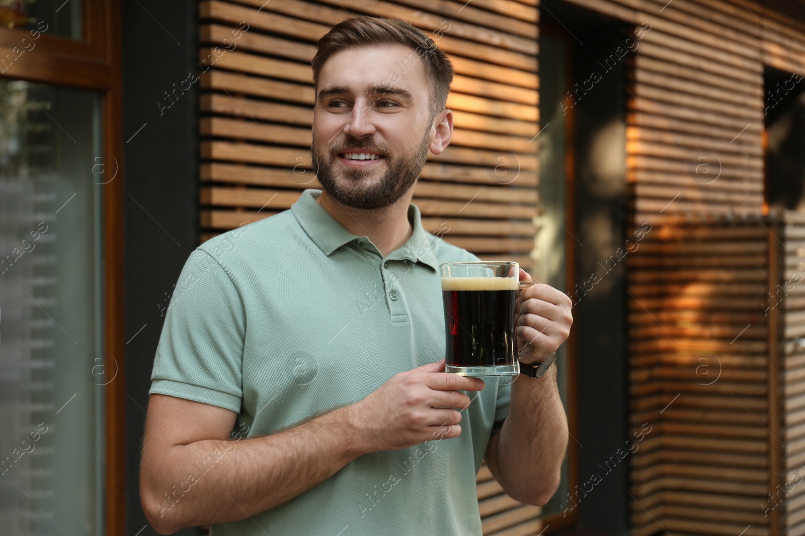 Photo of Handsome man with cold kvass outdoors. Traditional Russian summer drink