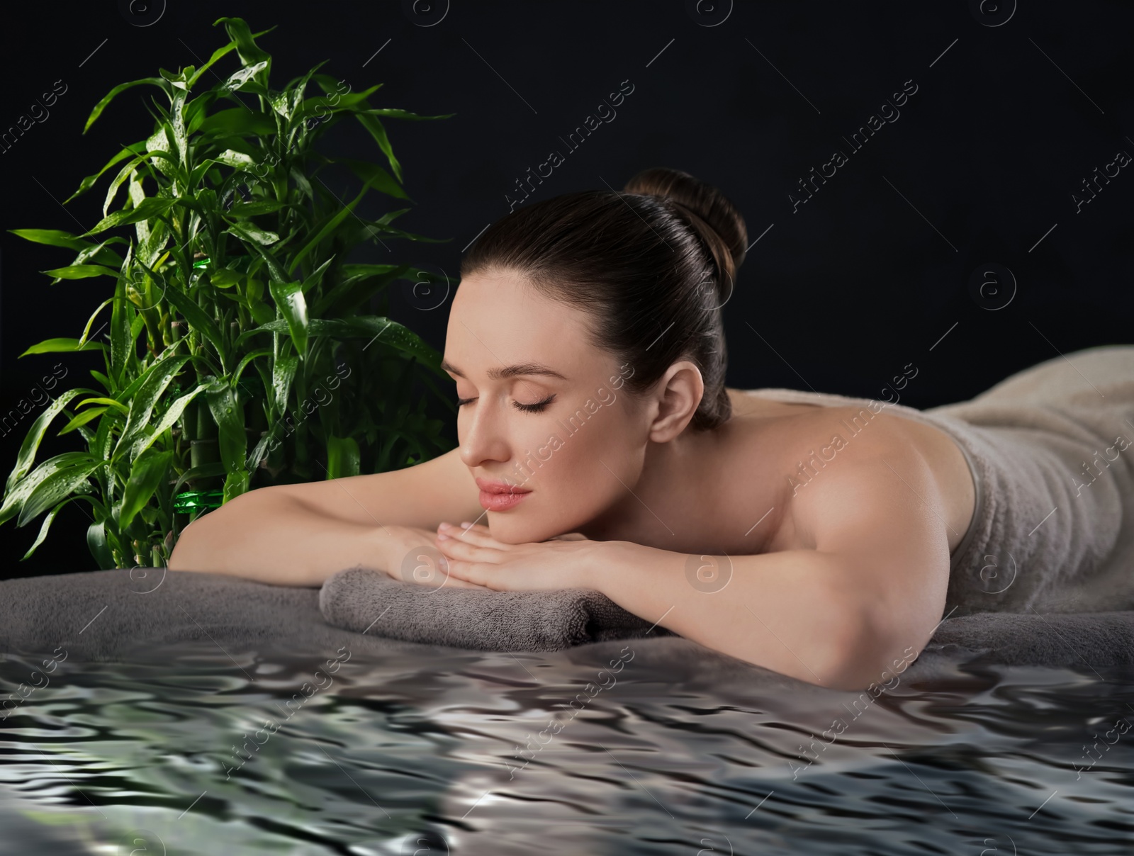 Image of Beautiful young woman relaxing in spa salon. Green bamboo stems on background