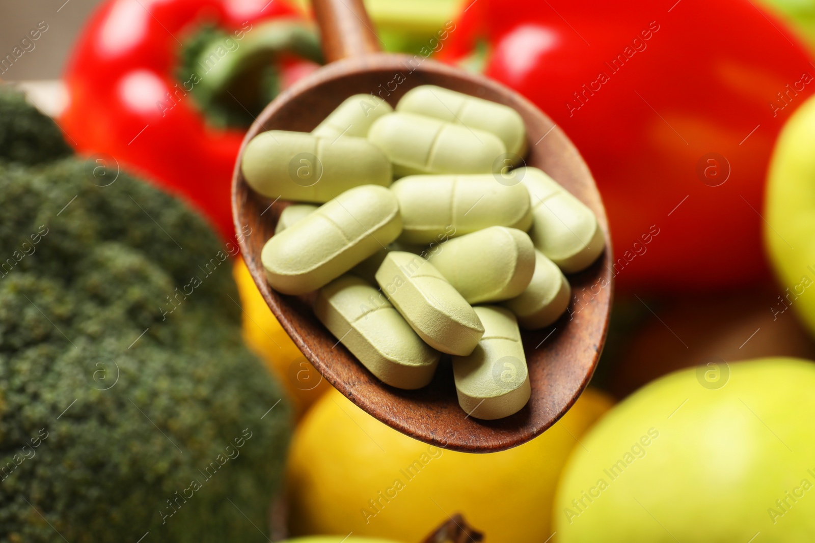 Photo of Dietary supplements. Spoon with pills over food products, closeup