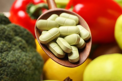 Photo of Dietary supplements. Spoon with pills over food products, closeup