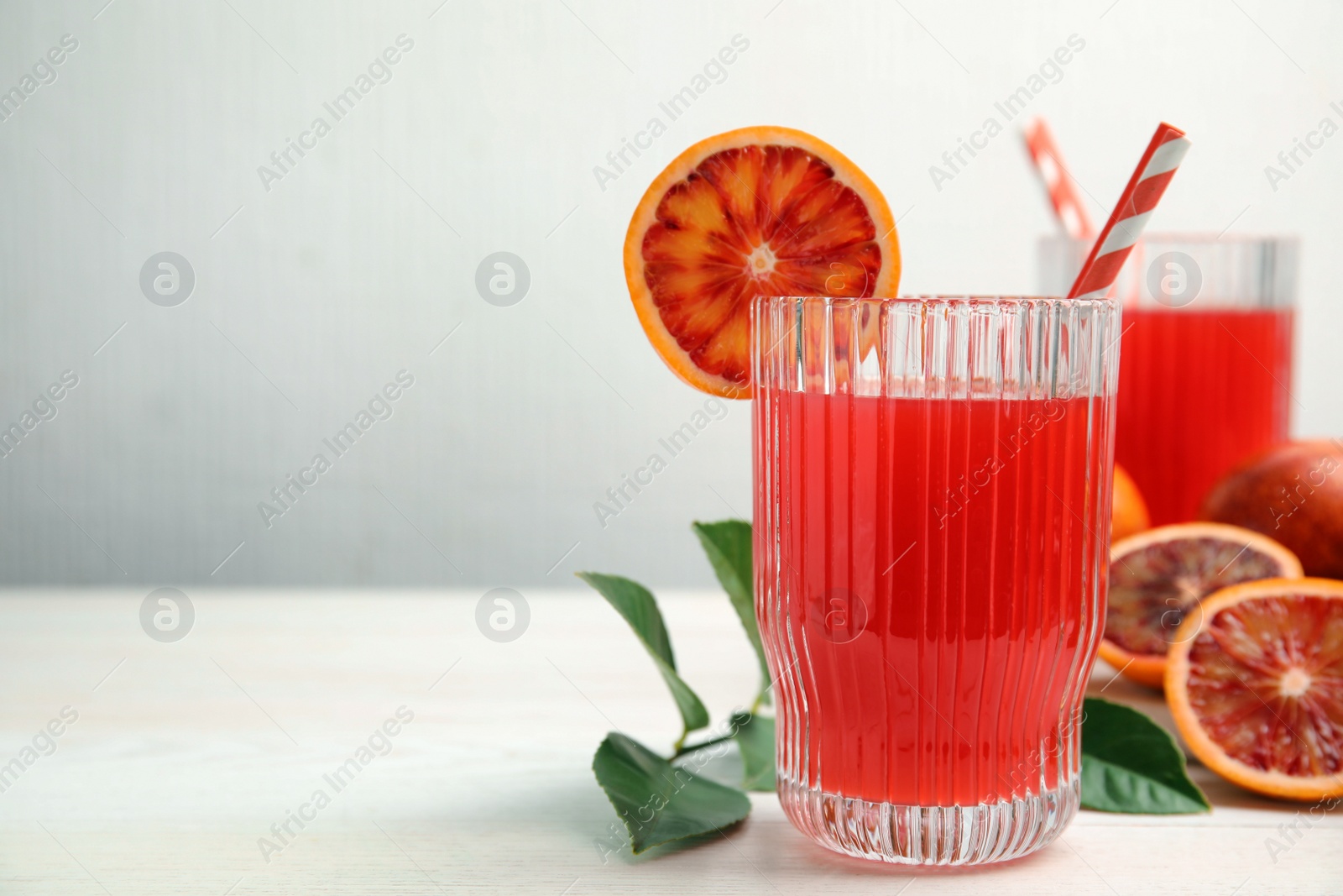 Photo of Tasty sicilian orange juice and fruits on white wooden table, space for text