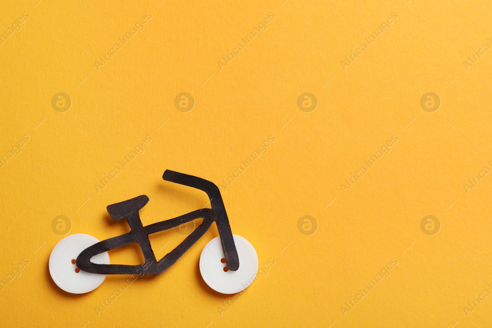 Photo of Bicycle made with buttons and black paper cutout on orange background, flat lay. Space for text