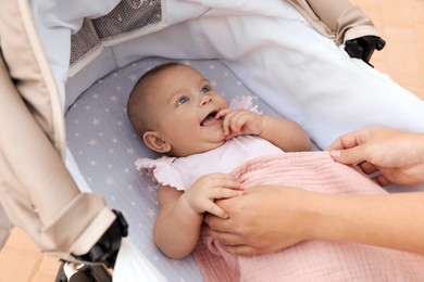 Photo of Mother covering her baby with blanket in stroller, closeup