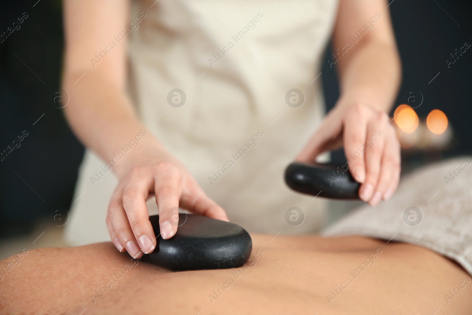 Photo of Man man receiving hot stone massage in spa salon, closeup