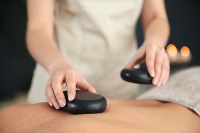 Man man receiving hot stone massage in spa salon, closeup