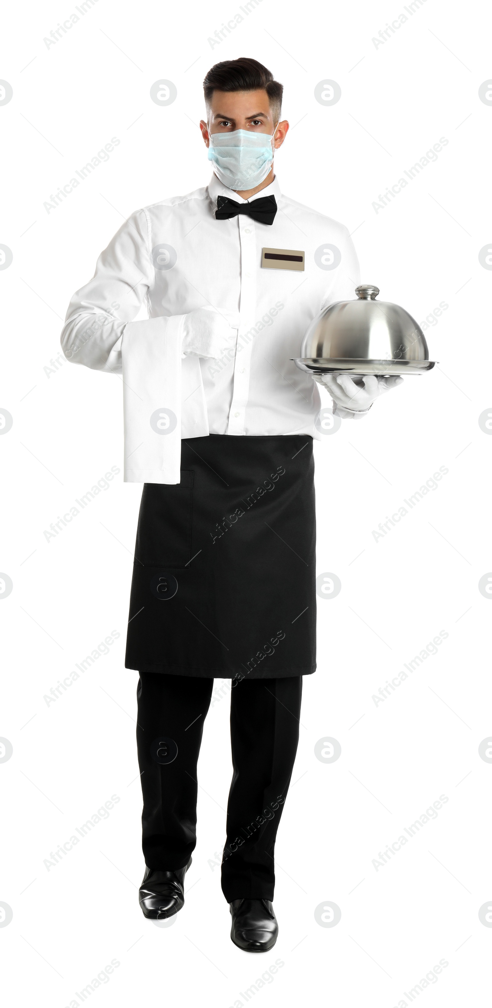 Photo of Waiter in medical face mask holding tray with lid on white background