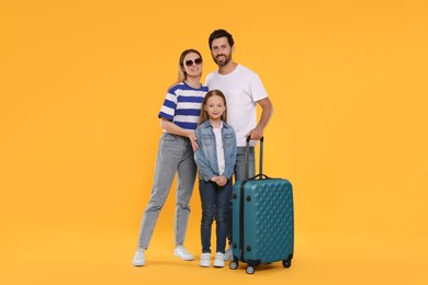 Photo of Happy family with green suitcase on orange background