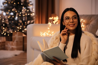 Photo of Young woman with book at home, space for text. Christmas celebration