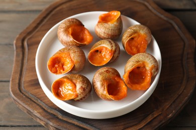 Photo of Delicious cooked snails on wooden table, closeup