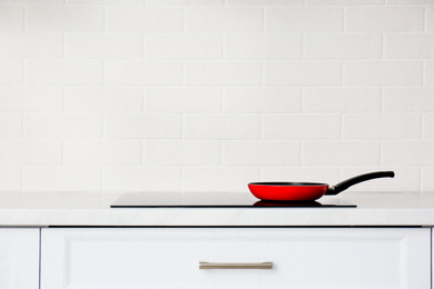 Photo of Frying pan on induction stove in kitchen, space for text