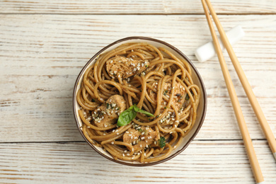 Photo of Tasty buckwheat noodles with meat on white wooden table, flat lay