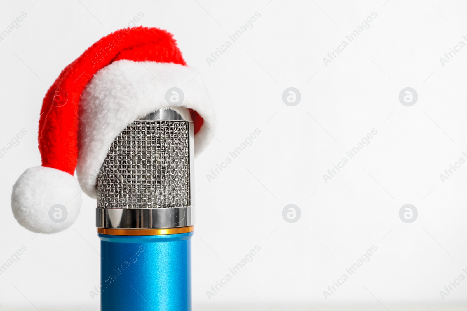 Photo of Microphone with Santa hat on white background, space for text. Christmas music