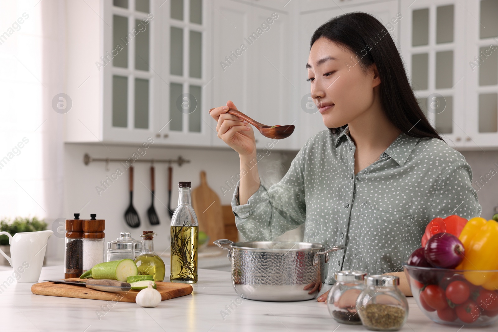 Photo of Beautiful woman tasting food after cooking in kitchen