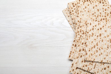 Photo of Stack of matzos on white wooden table, flat lay. Space for text
