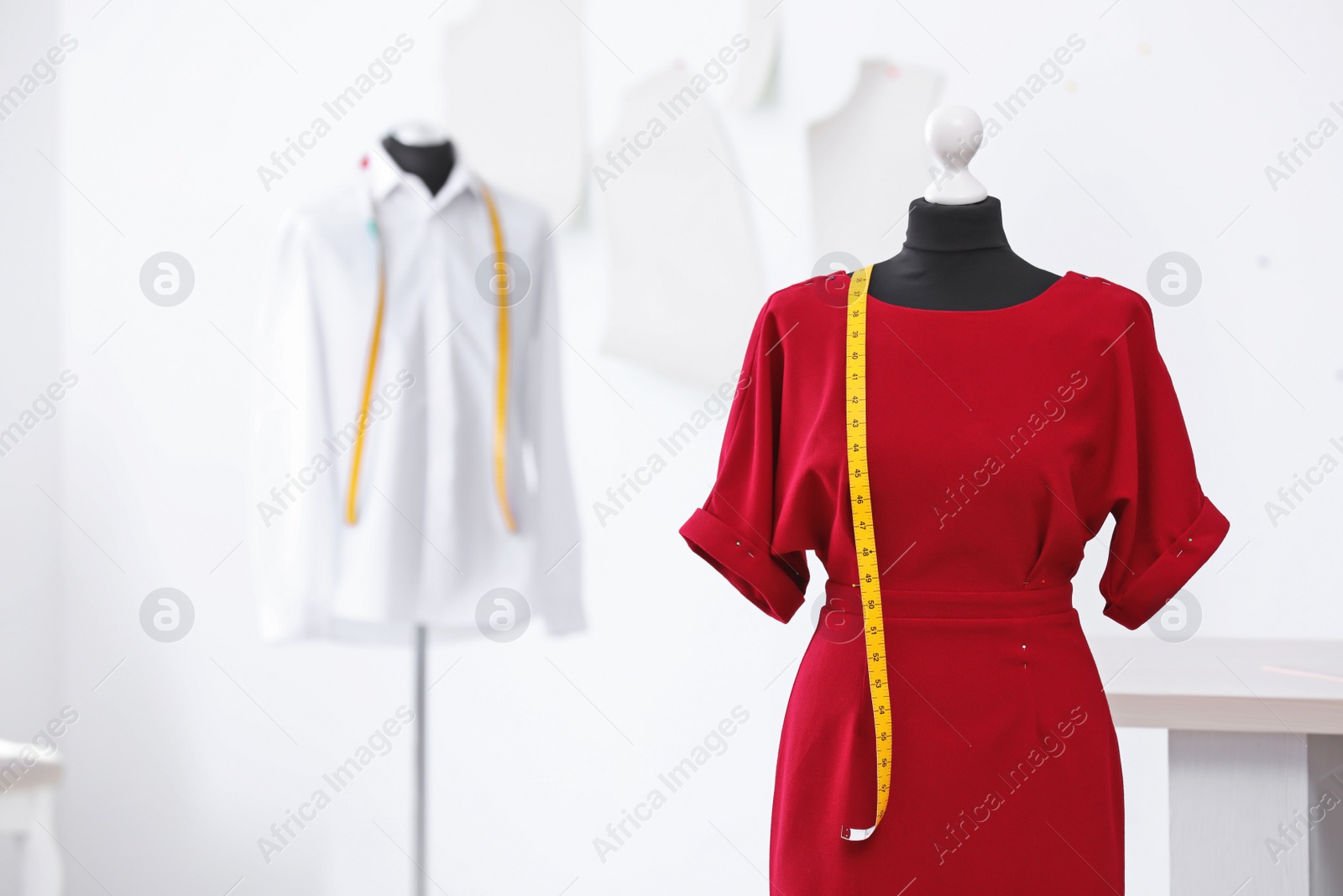 Photo of Mannequin with dress and measuring tape in tailor studio