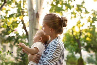 Teen nanny with cute baby in park on sunny day