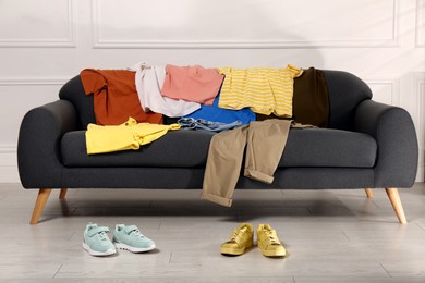 Shoes near sofa with different clothes indoors