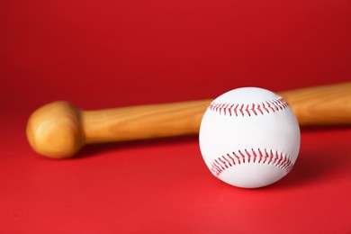 Photo of Wooden baseball bat and ball on red background. Sports equipment