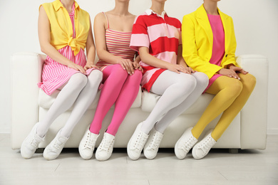 Women wearing colorful tights sitting on sofa indoors, closeup