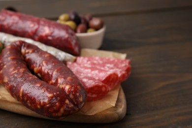 Photo of Different types of tasty sausages on wooden table, closeup. Space for text